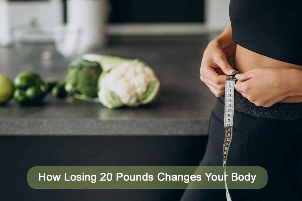 A woman in fitness clothing measures her waist with a tape measure in a kitchen, with fresh vegetables like cauliflower and green peppers on the counter, symbolizing healthy lifestyle changes.