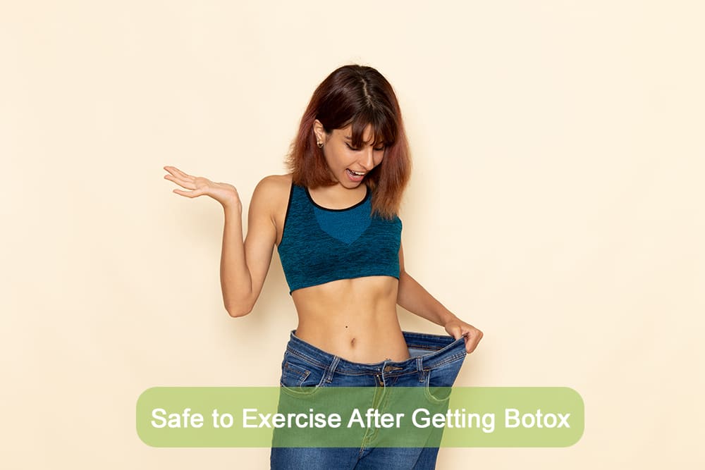 Fit young woman in sportswear showing off weight loss results with loose jeans