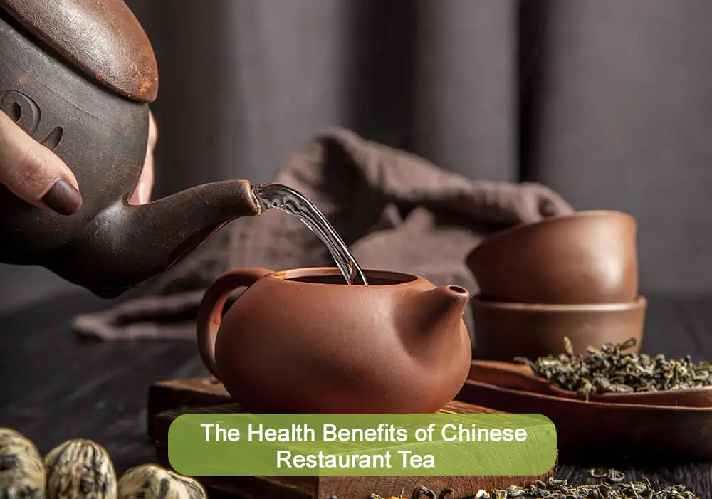 Traditional Chinese tea being poured into a clay teapot with loose tea leaves around